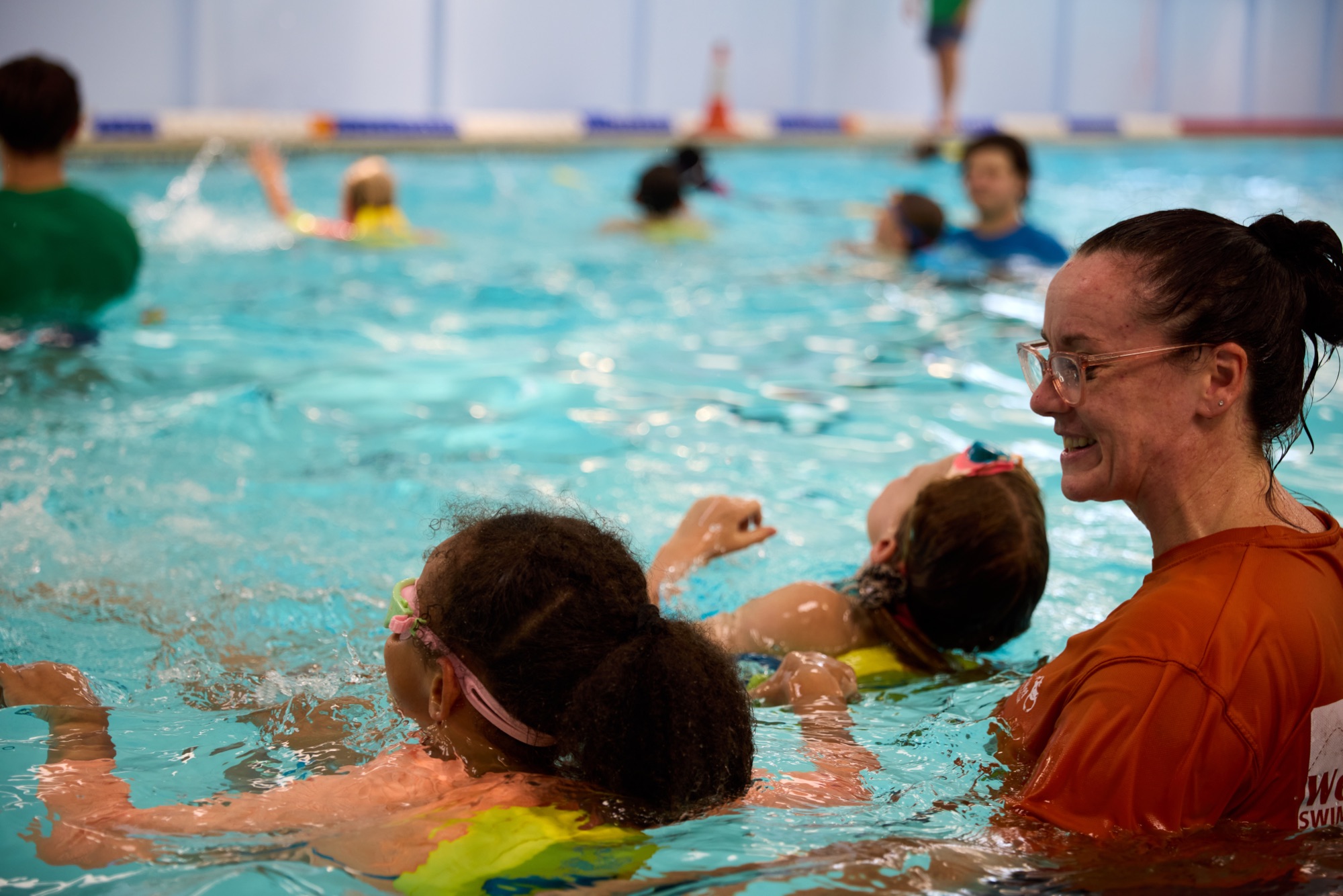 Wet Wet Wet Swim School instructor smiling with two children learning to float
